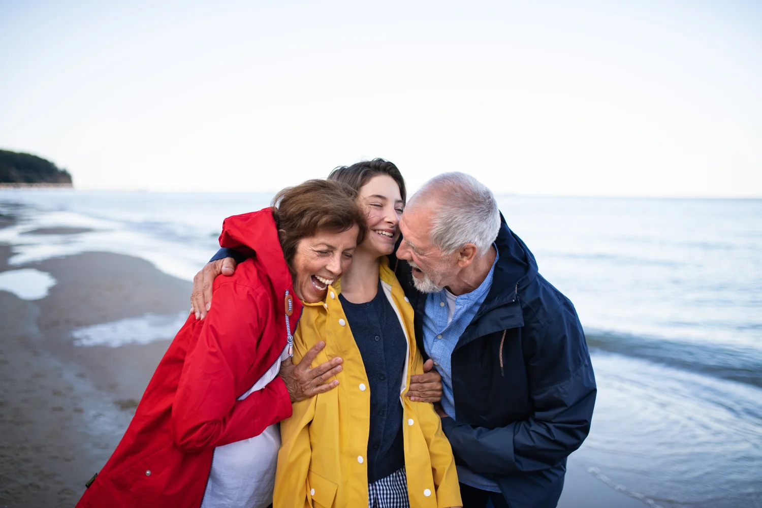 Three family members embracing on a beach